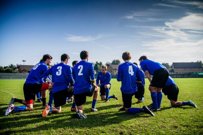 Gruppo di giocatore di sport in ginocchio sul campo